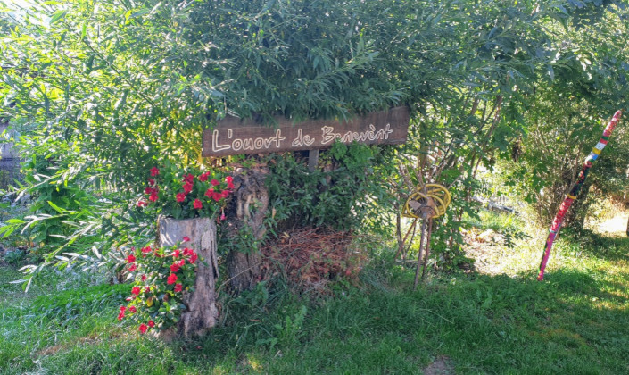 Sur un arbre, un panneau sur lequel est ecrit l'Ouort de Bénévent. Autour, la vegetation est luxuriante.