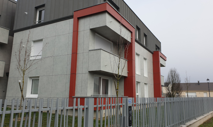Vue exterieur de l'immeuble gris aux liserets metalliques rouges et au toit de zinc.