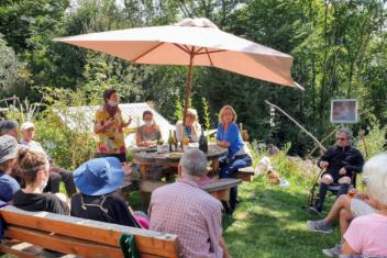 Personnes assises en cercle sur des bancs et chaises dans un jardin.