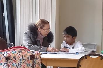 Une femme aide un enfant à faire ses devoirs. 