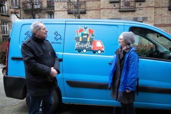 Deux personnes discutent devant la camionette bleue Bricobus