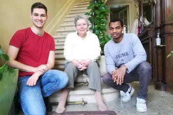 Deux jeunes et une personne âgée assis sur les marches d'un escalier